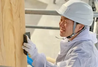 画像：作業員が木目の板を擦っている様子。